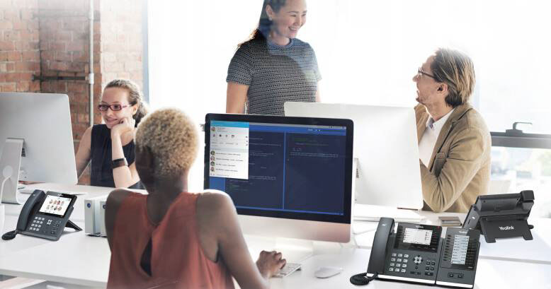 Team collaborating in modern office with Yealink business phones